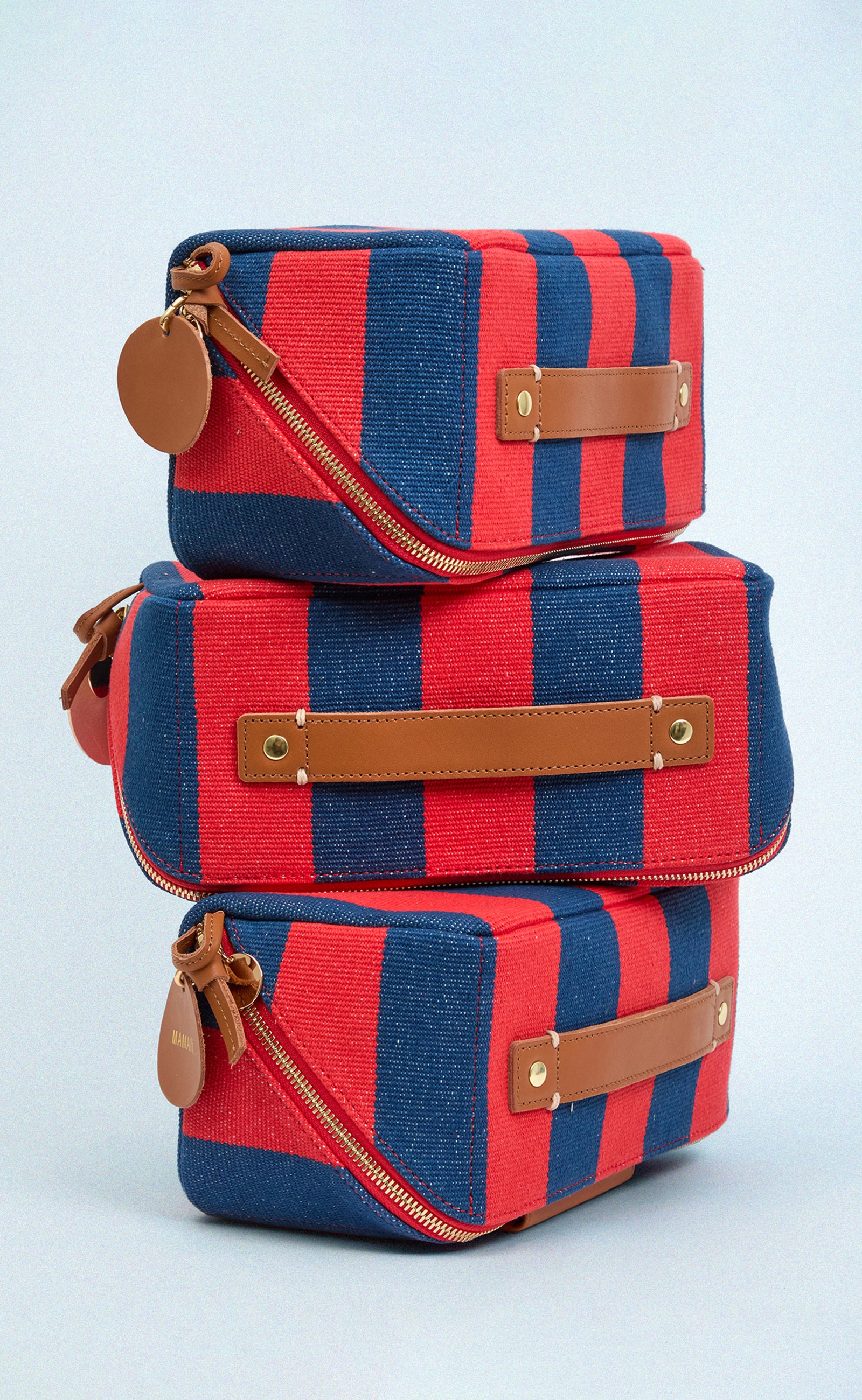 Three Poppy and French Blue Canvas Stripe Vacances stacked on top of each other. 
