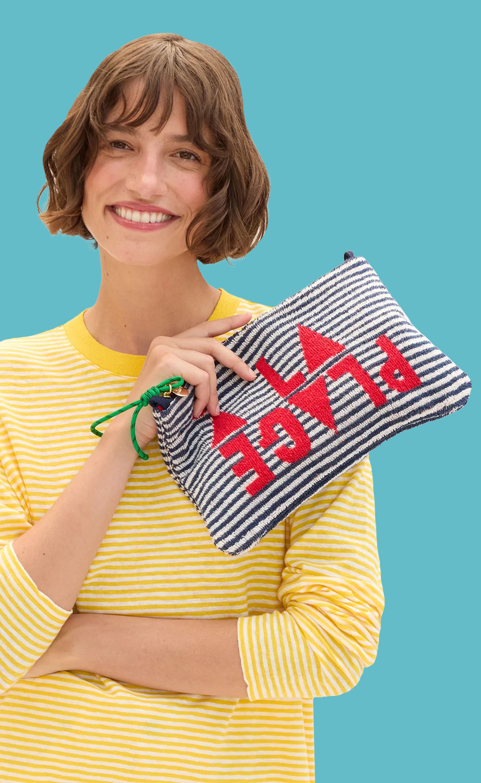 Model wearing the Snapdragon and Cream Mini Stripe Long Sleeve Tee and holding the À la Plage Flat Clutch with Tabs.
